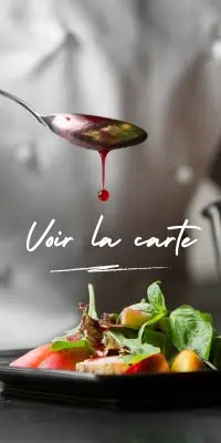 Goutte de sauce rouge tombant d'une cuillère au-dessus d'une assiette de salade colorée avec laitue, tomates et morceaux de fruits, avec le texte blanc "Voir la carte" au centre